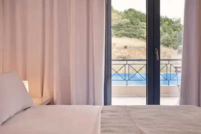 a bedroom with a bed and a view of a balcony at Augoustos ECO luxury apartments with pool in Aghia Marina