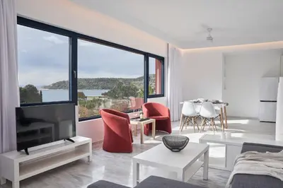a living room with a tv and a large window at Augoustos ECO luxury apartments with pool in Aghia Marina