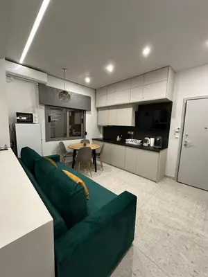 a living room with a green couch and a kitchen at Smart Lux Apartment B in Athens