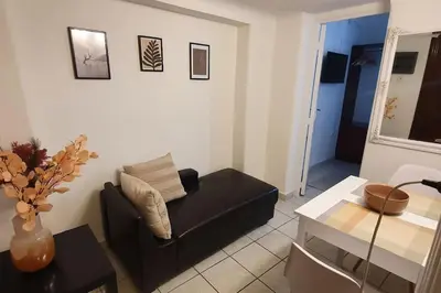 a living room with a black couch and a table at Lefti's Cosy Studio 40m2, Metro 7' in Athens