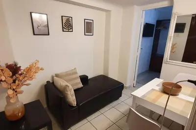a living room with a black couch and a table at Lefti's Cosy Studio 40m2, Metro 7' in Athens