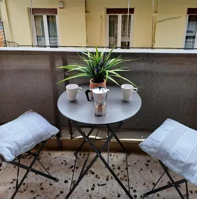 a table with two cups and a plant on a balcony at Lovely Studio Apartment For 2 Ppl in Athens in Athens