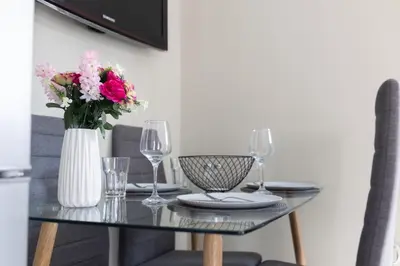 a glass table with a vase of flowers and wine glasses at AIOLOS LUXURY agios dimitrios center apartment 4 in Athens