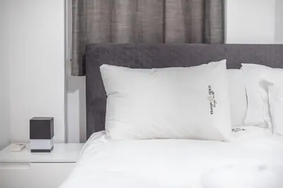 a bed with white sheets and pillows with a alarm clock at Iguana Gold Luxury Suites 2 ( 1 min from Ermou street) in Athens