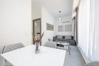 a white living room with a table and chairs at Iguana Gold Luxury Suites 2 ( 1 min from Ermou street) in Athens