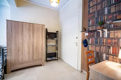 a room with a wooden cabinet and a wall of books at Acropolis Athens 1 bedroom 4 pers apt by MPS in Athens