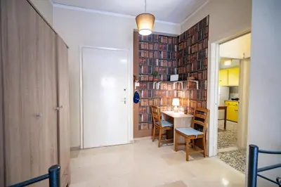 a room with a table and chairs and a wall of books at Acropolis Athens 1 bedroom 4 pers apt by MPS in Athens