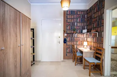 a room with a table and chairs and a wall of books at Acropolis Athens 1 bedroom 4 pers apt by MPS in Athens