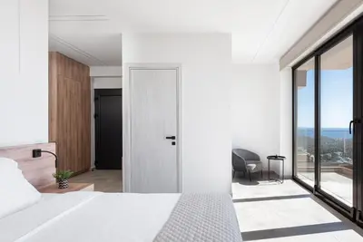 a bedroom with a white bed and a large window at Saronida Hills in Saronida