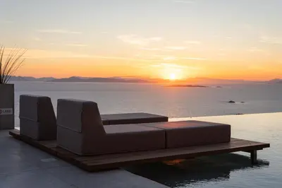 a couch sitting on a table in the water with the sunset at Saronida Hills in Saronida