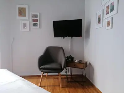 a bedroom with a chair and a television on a wall at Minimal Studio Varnava Square - Kallimarmaro Area in Athens