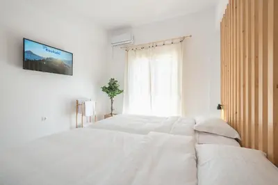 a bedroom with a white bed with a tv on the wall at ATHENIAN HOME Near Acropolis in Athens