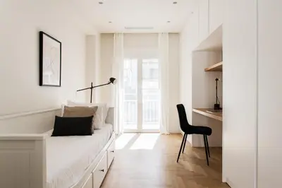 a white bedroom with a bed and a black chair at Spectacular 3BR Apartment in Pangrati by UPSTREET in Athens