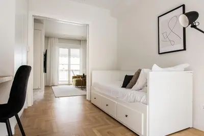 a white bedroom with a white bed and a black chair at Spectacular 3BR Apartment in Pangrati by UPSTREET in Athens