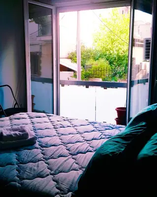 a bedroom with a bed and a large window at Κεντρικό διαμερισμα άνετο κ ήσυχο in Athens