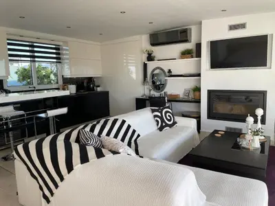 a living room with a white couch and a tv at Luxury Penthouse Studio with Sea View, Palaio Faliro in Athens