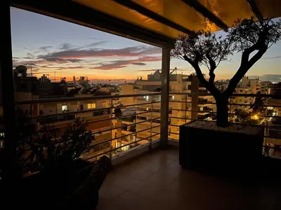 a view of a city at sunset from a balcony at Luxury Penthouse Studio with Sea View, Palaio Faliro in Athens