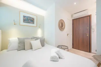 a bedroom with a white bed with a wooden door at SYNTAGMA MINI in Athens