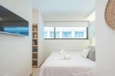 a white bedroom with a bed and a window at SYNTAGMA MINI in Athens