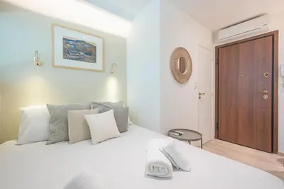 a bedroom with a white bed and a wooden door at SYNTAGMA MINI in Athens