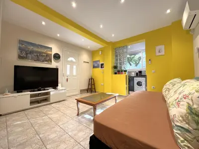 a living room with yellow walls and a flat screen tv at Historic Center getaway 10'walk to Acropolis hill in Athens