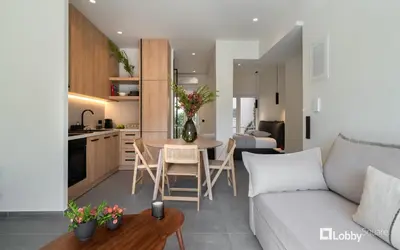 a living room and kitchen with a couch and a table at La Mer Apartment by LobbySquare in Piraeus
