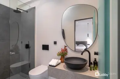 a bathroom with a black sink and a mirror at La Mer Apartment by LobbySquare in Piraeus