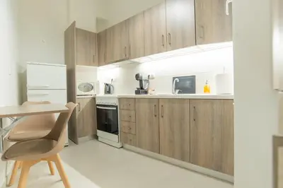 a kitchen with wooden cabinets and a table and a chair at Comfy Sweet Home in Athens
