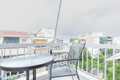 a table and chair on a balcony with buildings at Comfy Sweet Home in Athens