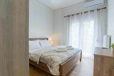 a bedroom with a bed and a large window at Comfy Sweet Home in Athens