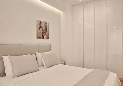 a bedroom with a white bed with a painting on the wall at Cute n Comfort Luxury Condo in Kolonaki in Athens