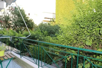a green railing next to a garden with plants at Glyfada Path of Poets in Athens