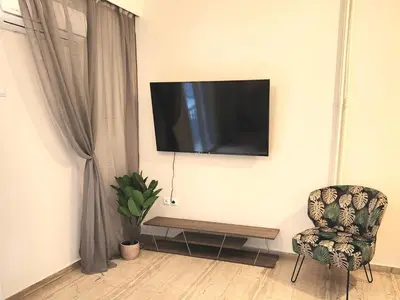 a room with a tv on the wall with a chair at Cute Nikis Apartment VIPGreece in Athens