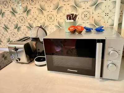 a microwave sitting on a counter with three cups on it at Cute Nikis Apartment VIPGreece in Athens