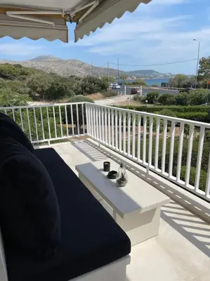 a balcony with a couch and a table on a porch at Lagonisi Luxury apartment 2 by the sea in Lagonissi