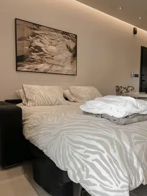 a white bed in a bedroom with a painting on the wall at Lagonisi Luxury apartment 2 by the sea in Lagonissi