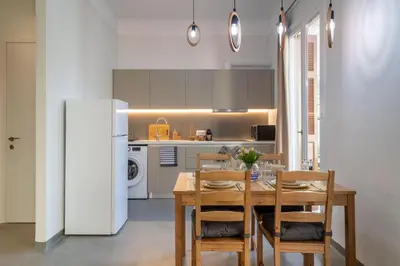 a kitchen with a wooden table with chairs and a refrigerator at Christiana's lovely apartment in Psyri, Athens in Athens