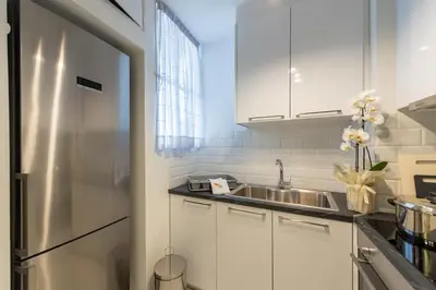 a kitchen with white cabinets and a stainless steel refrigerator at MEDLUXE COZY APARTMENT! in Athens
