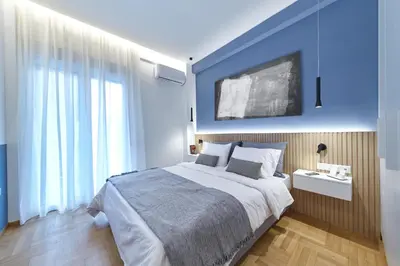 a bedroom with a large bed with a blue wall at Artemis Suite at Acropolis Historic Center in Athens