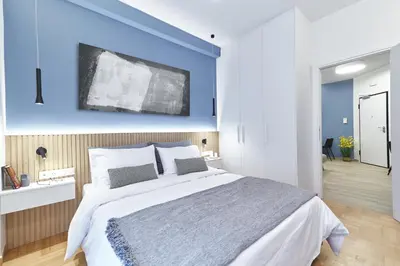 a bedroom with a large bed with a blue wall at Artemis Suite at Acropolis Historic Center in Athens