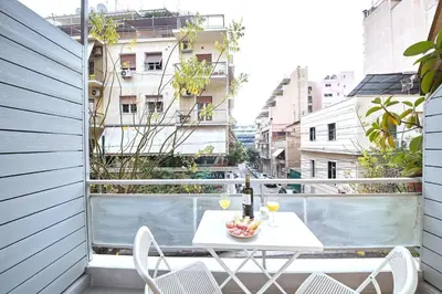 a white table and chairs on a balcony with a building at Artemis Suite at Acropolis Historic Center in Athens