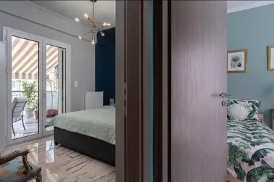 a bedroom with a bed and a door leading to a balcony at Artistic apt in vibrant Gazi with large terrace by GHH in Athens