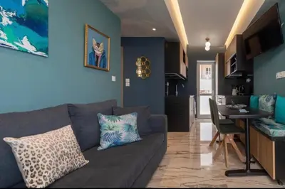 a living room with a gray couch and a kitchen at Artistic apt in vibrant Gazi with large terrace by GHH in Athens