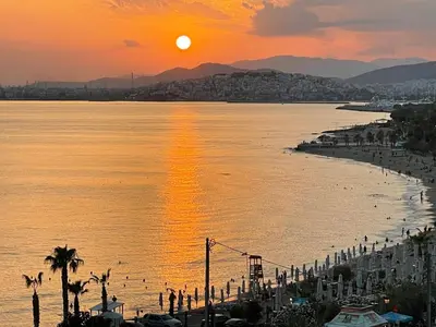 a sunset over a body of water with a city at Athens Edem Beach Penthouse, panoramic sea view in Athens