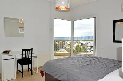 a bedroom with a bed and a desk and a window at Athens Edem Beach Penthouse, panoramic sea view in Athens