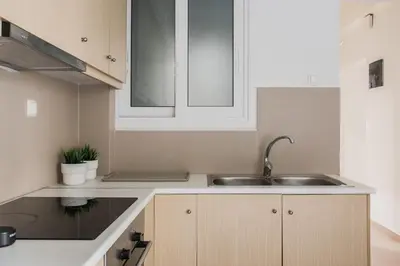 a kitchen with a sink and white cabinets at Groovy 2BR Apartment in Koukaki by UPSTREET in Athens