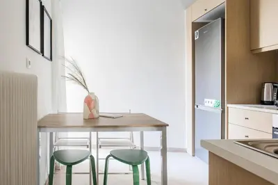 a kitchen with a wooden table and two green stools at Groovy 2BR Apartment in Koukaki by UPSTREET in Athens