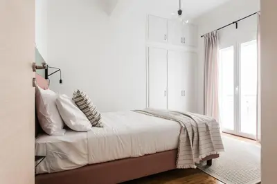 a bedroom with a bed with white sheets and a window at Groovy 2BR Apartment in Koukaki by UPSTREET in Athens
