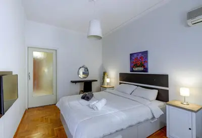 a white bedroom with a large bed and a television at Sunny all day apartment near Athens city center in Athens