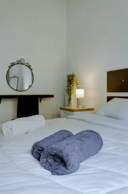 a white bed with two purple towels on it at Sunny all day apartment near Athens city center in Athens